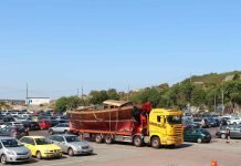 The Benefits of Reliable Vehicle Shipping Services in Idaho for Moms and Families Yellow truck hauling wooden boat in parking lot.