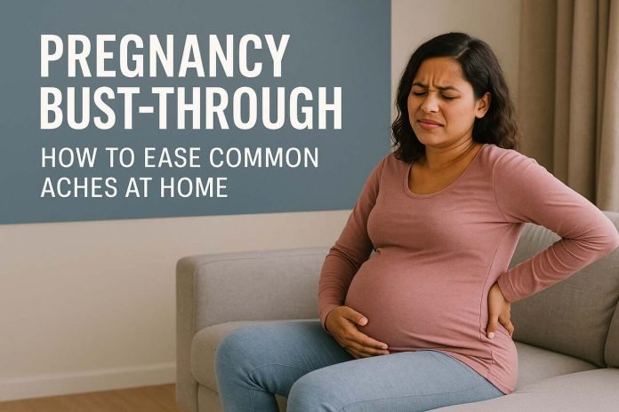 Pregnant woman in a pink long-sleeve shirt and blue jeans sitting on a couch, holding her lower back in discomfort
