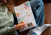 The Ultimate Pregnancy Memory Checklist (That Doesn’t Involve Scrapbooking) Woman journaling with colorful scrapbook elements in a notebook.