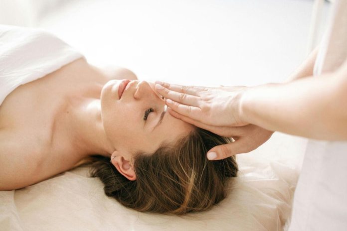 Woman receiving gentle Reiki or energy healing therapy at a spa.
