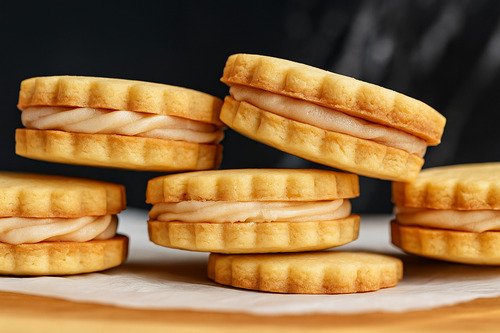 Close-up of stacked vanilla sandwich cookies with creamy filling.